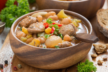 delicious vegetable stew with sausages in a wooden bowl