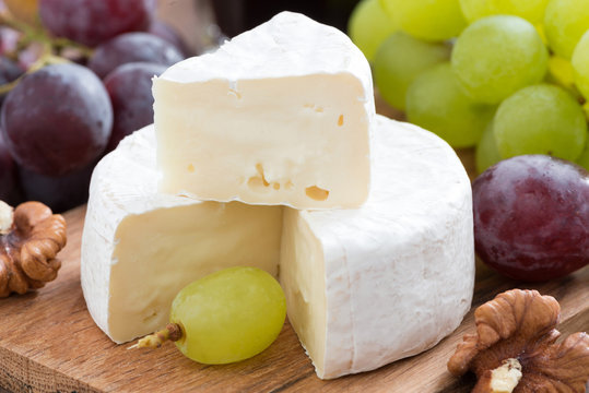 fresh camembert on a wooden board and grapes, close-up