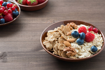 oatmeal and muesli in a bowl, fresh berries on wooden table