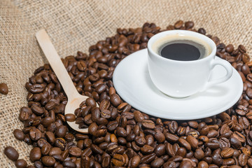 coffee beans with wooden spoon and cup of coffee.