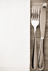 knife and fork at napkin on wood