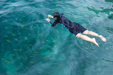Young lady snorkeling in a turquoise tropical sea