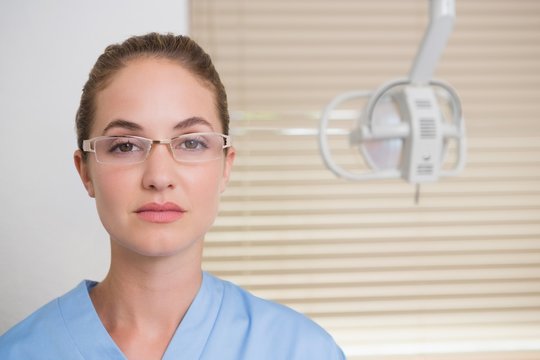 Dentist in blue scrubs looking at camera