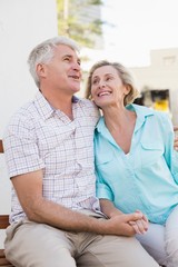 Happy mature couple sitting on bench in the city