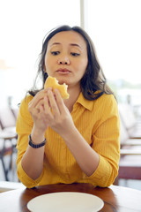 Pretty Young Woman Eating Burger In Cafe