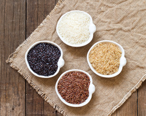 Variety of rice in bowls on wooden table