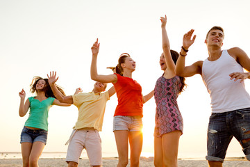 Obraz premium smiling friends dancing on summer beach
