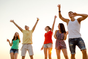 Obraz premium smiling friends dancing on summer beach