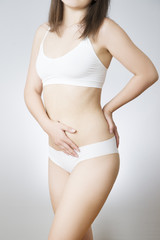 Young woman in white lingerie on a gray background