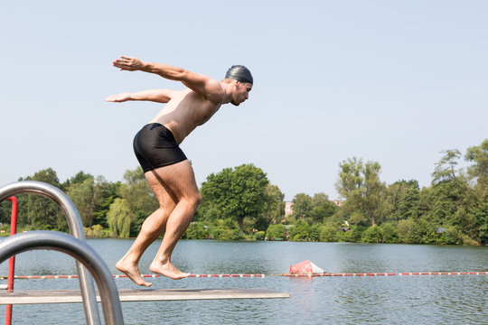 Man Jumping Off Diving Board At Swimming Pool