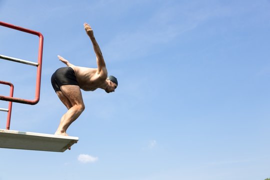 Man jumping off diving board at swimming pool