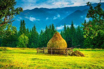 Fototapety  Amazing mountain landscape with fog and a haystack