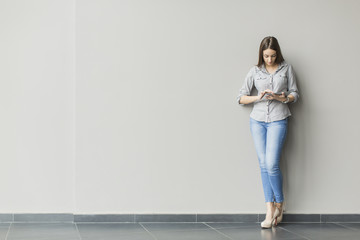 Woman with tablet by the wall