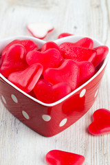 Fototapeta na wymiar heart-shaped candies in a bowl on wooden surface