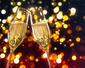 champagne flutes with golden bubbles on colorful bokeh