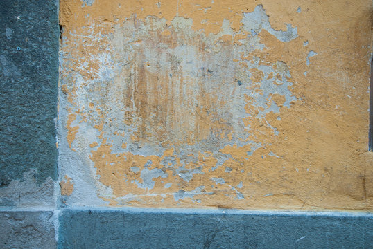 Muro giallo con graffi, intonaco danneggiato
