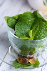 Mint leaves in glass cup on color wooden background