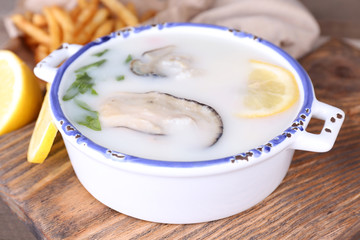 Tasty soup with oysters on wooden table