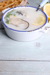 Tasty soup with oysters on wooden table