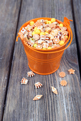 Beads in metal bucket on wooden background