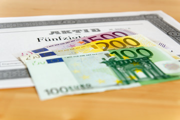 Aktie mit aufgefächerten Geldscheinen und geringer Tiefenschärfe