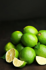 Fresh juicy limes on wooden table, on dark background