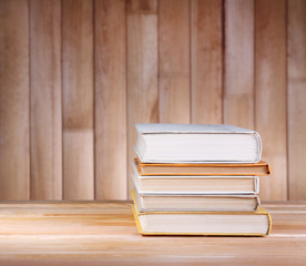 Books on wooden table on wooden wall background