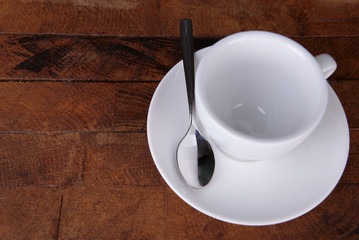Empty cup with tea spoon on wooden background