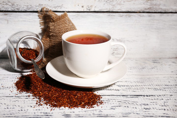 Cup of tasty rooibos tea, on old white wooden table