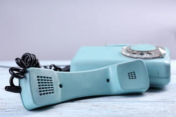 Retro turquoise telephone on wooden table, close up