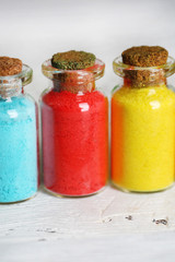 Bottles with colorful dry pigments on wooden background