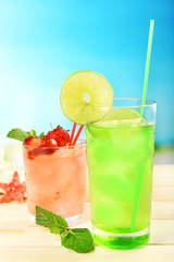 Refreshing cocktail on wooden table on blue background