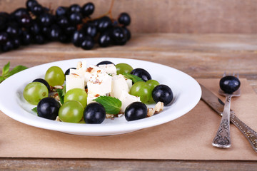 tasty salad with grape and cheese on wooden table