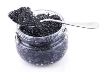 Glass jar and spoon of black caviar isolated on white