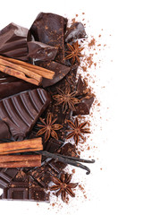Cracked chocolate bar with spices on white background