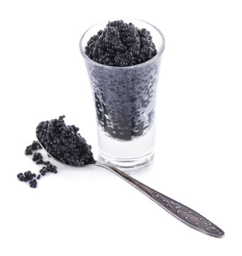 Glass and spoon of black caviar isolated on white