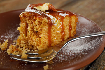 Half eaten delicious cake piece on plate on wooden table
