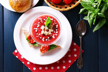 Gazpacho soup in glass bowl, on color wooden background