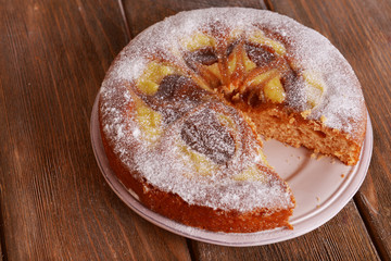 Delicious cake with caramel on plate on wooden table