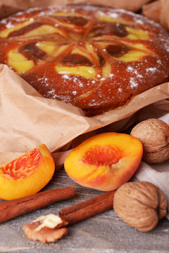 Delicious cake with peach and nuts on wooden table close up