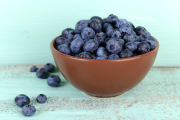 Tasty ripe blueberries in bowl, on wooden table