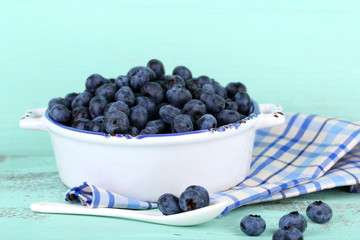Tasty ripe blueberries in bowl, on wooden table