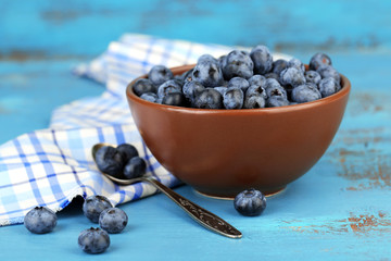 Tasty ripe blueberries in bowl, on wooden table