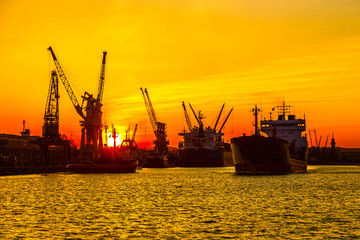 Fototapeta premium Silhouette of sea port cranes over sunset