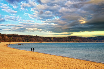 Fototapeta premium Couple walking on an empty beach a cloudy morning