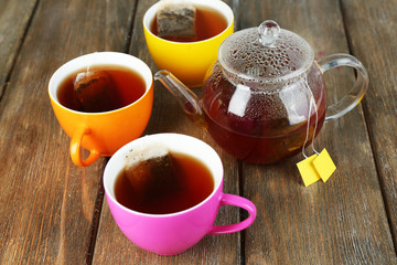 Cups of tea, teapot and tea bags on wooden table close-up