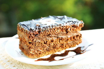 Chocolate cake on plate, on wooden table, on bright background