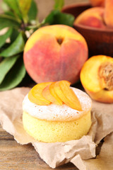 Tasty mini cakes with fresh peach, on wooden table