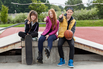 Teenagers thumbs up at skatepark