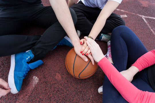 Friends holding hands on basketball